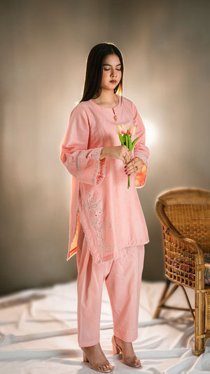 Woman in a pink traditional outfit holding flowers against a neutral background