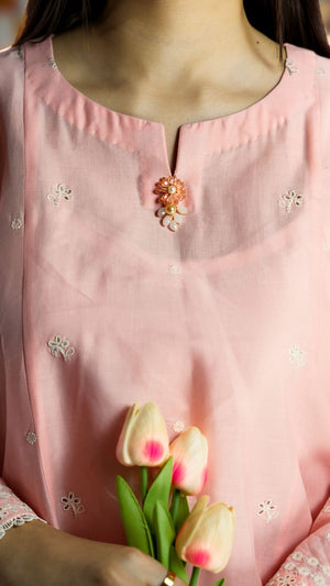 Person wearing a pink traditional outfit with floral embroidery, holding tulips.