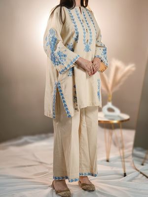 Beige traditional outfit with blue embroidery on a neutral background