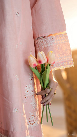Person wearing a pink dress with lace details holding tulips against a blurred background