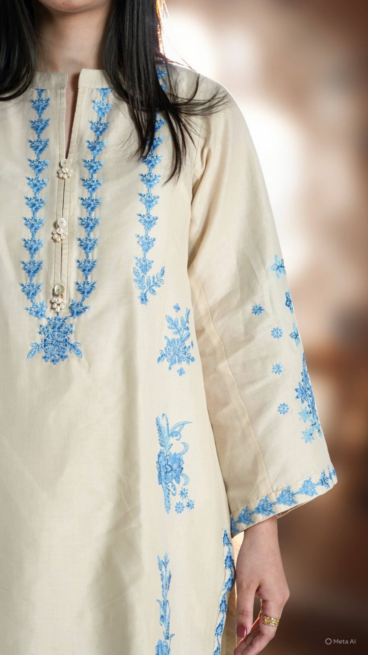 Beige kurta with blue floral embroidery on a blurred background